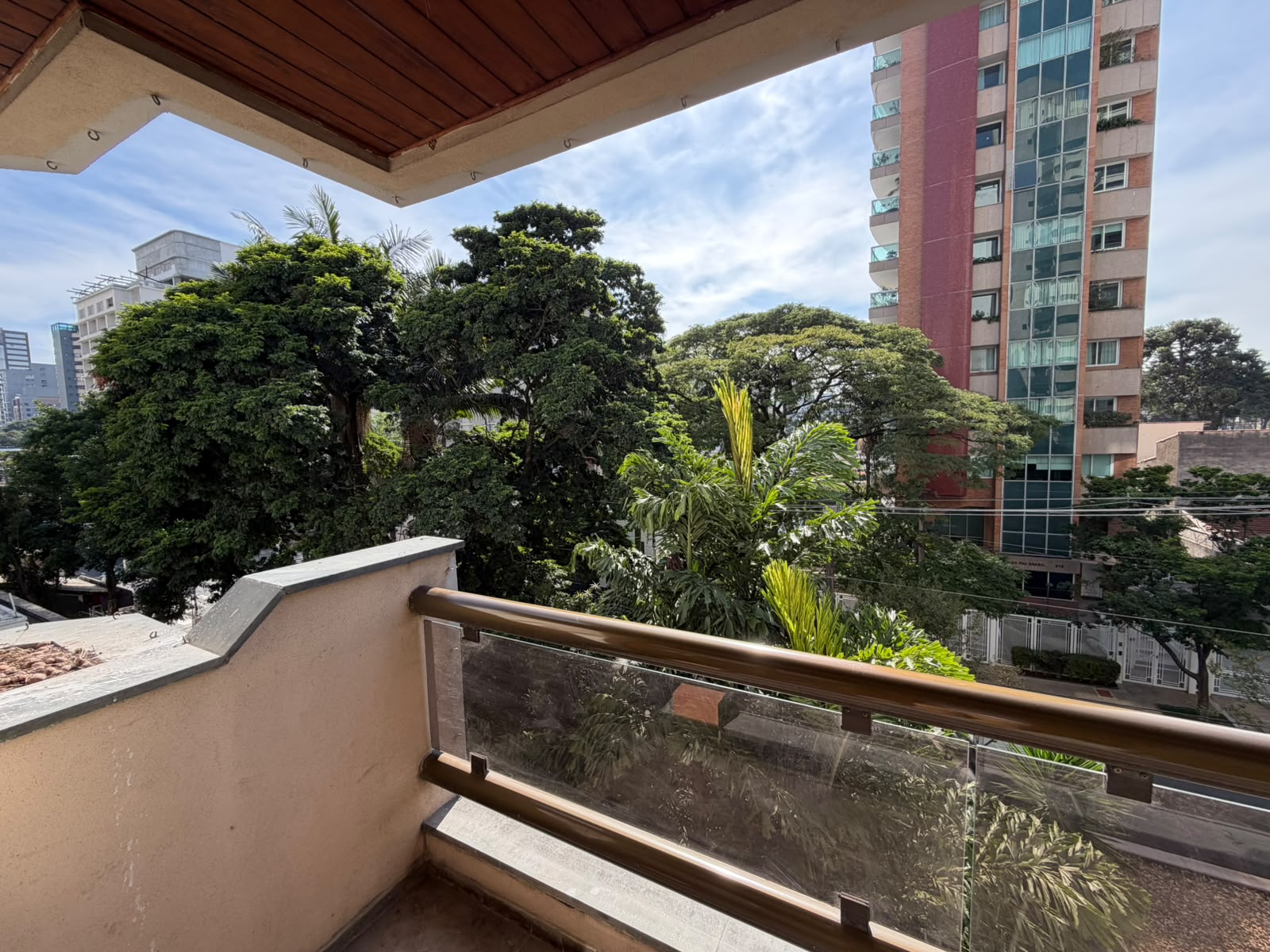 Vista da varanda da sala: arborização ao lado e prédios vizinhos recuados